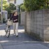 見通しの悪い住宅街の角で、自転車を降りて押しながら進む47歳の瑛里のイメージ