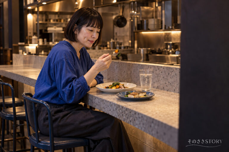 小さな洋食店のカウンターで、1人分の料理を選んで夕食を食べる50歳の佳乃を描いたイメージ