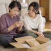 居間で届いたコーヒーの箱を前に、スマートフォンの注文内容を確認する母娘