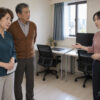 息子家族のマンションの仕事部屋で、同居について話す65歳の志津、67歳の康平と息子の妻・奈緒を描いたイメージ