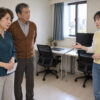 息子家族のマンションの仕事部屋で、同居について話す65歳の志津、67歳の康平と30代の息子の妻・奈緒を描いたイメージ